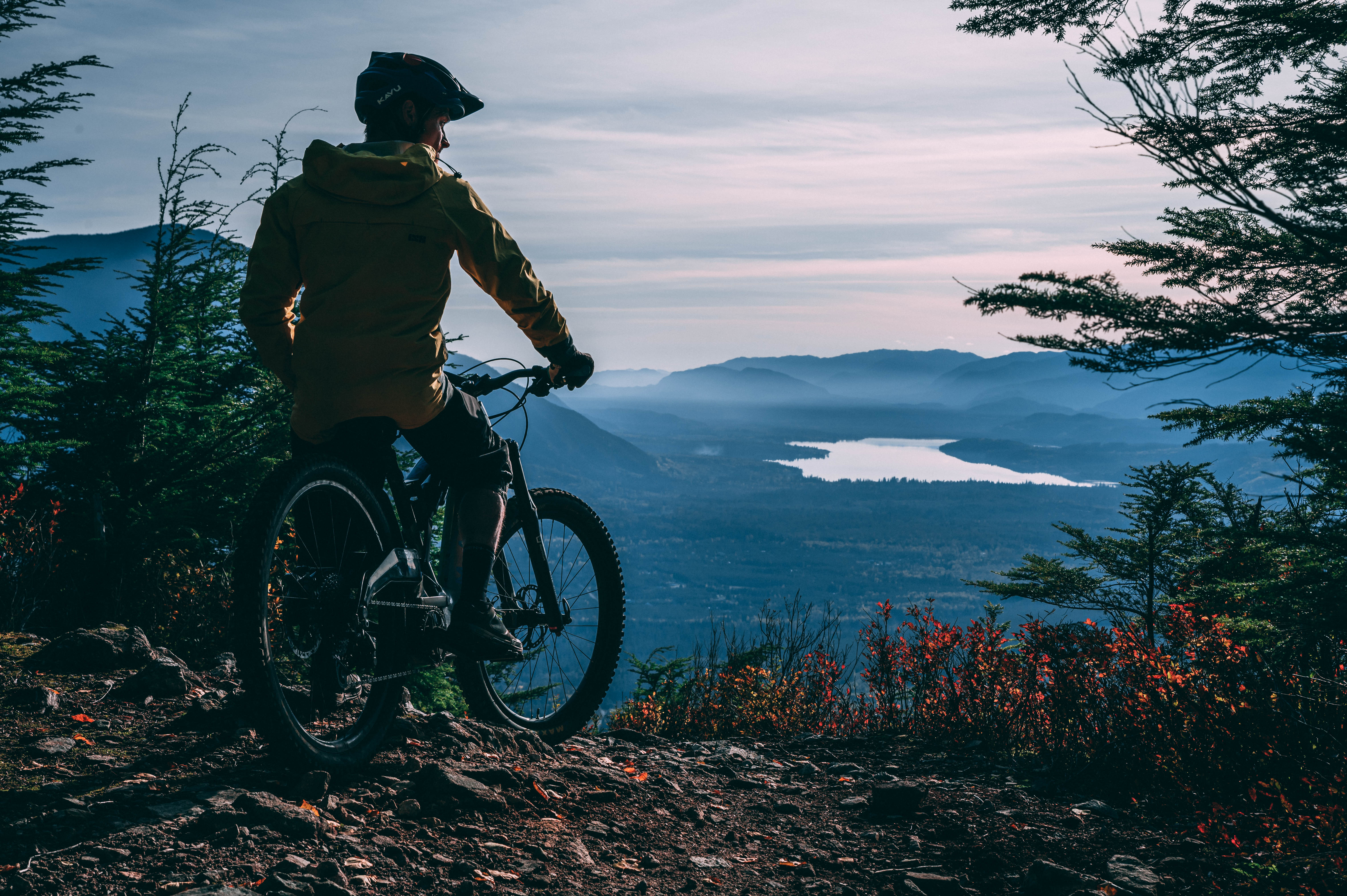 Image of mountain biker Mark Matthews taking in the view of forests and water from top of Terrace Mountain in Northern BC