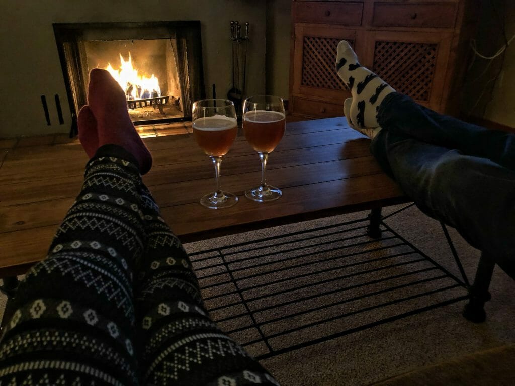 A pair of beers next to a cozy fireplace
